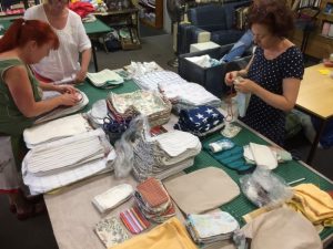 Women working with piles of fabric around a table