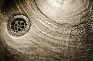 water going down the drain of a stainless steel sink