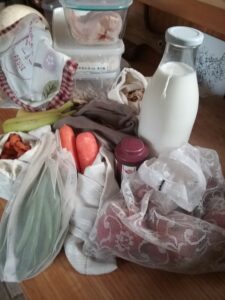 image of shopping in non-plastic re-usable bags or containers from home - milk, dry goods, meat, fruit and veg.