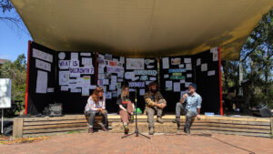 People seated and chatting on a mini-stage at a Degrowth Festival display